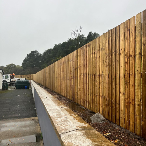 wooden fence along driveway with trees in background showing three wooden posts