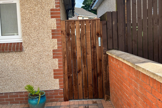 wooden gate leading to a courtyard featuring a potted plant brick wall and fence design three decorative elements